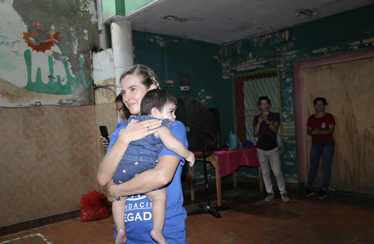 A volunteer holding a small child close during a community visit in Paraguay